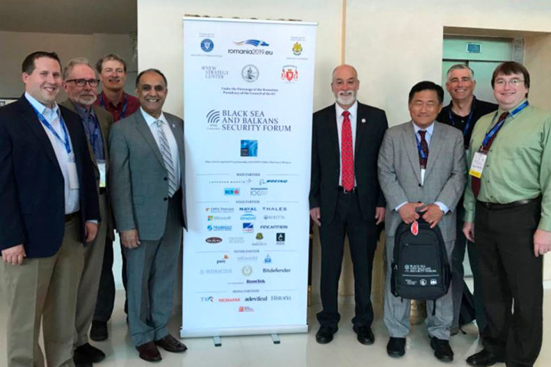 Group of forum participants standing next to a banner.