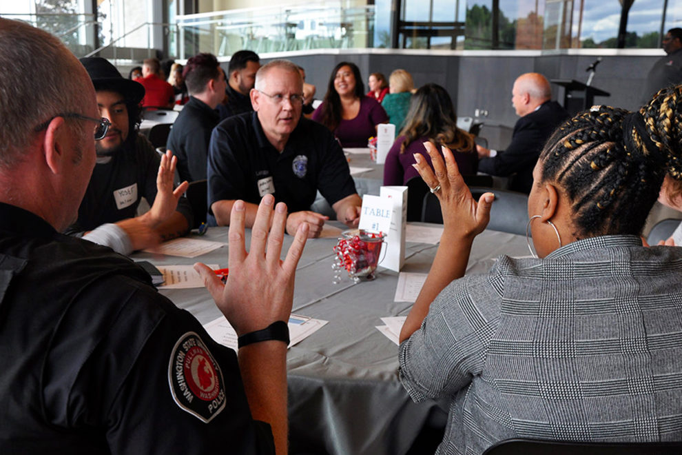 WSU police officers talk with students while seated at a table.