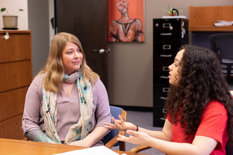 Two women discuss improvements to Executive Policy 15.
