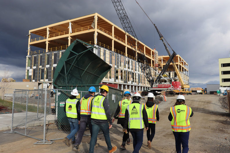 People with hard hats and safety vests walking through a construction site.