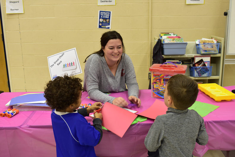 A College of Education student interacts with two young children.