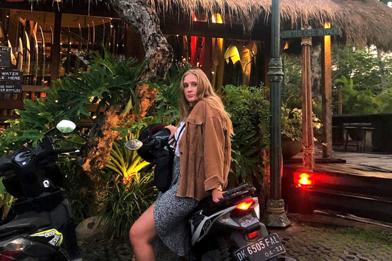 Doran sitting on a motorized scooter outside an Indonesian establishment.