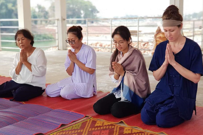Four women practice guided meditation at a temple in Thailand.