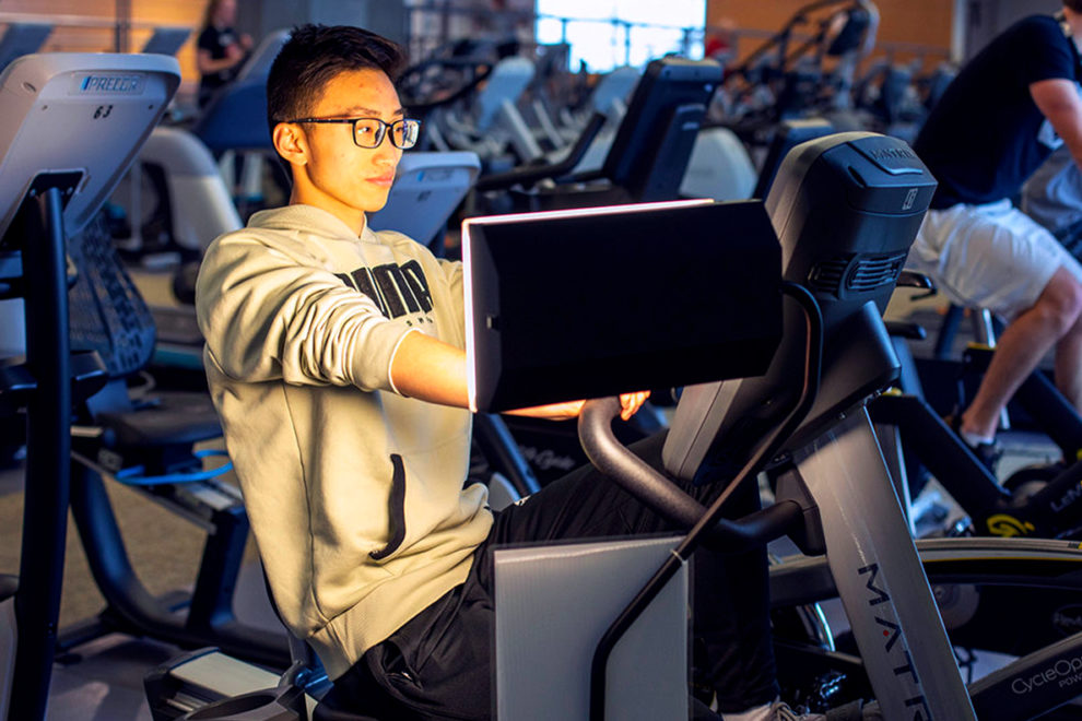 Mike Chan using exercise equipment next to a therapy light.