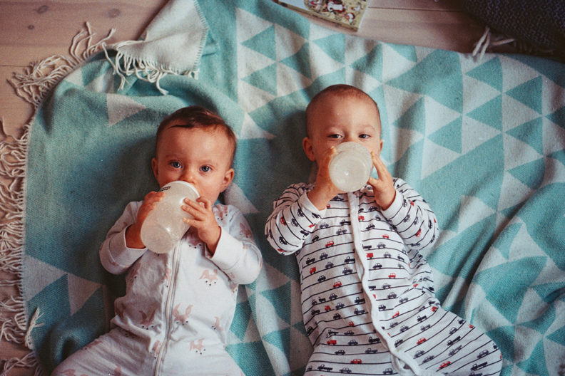 Two babies lying on a blanket.
