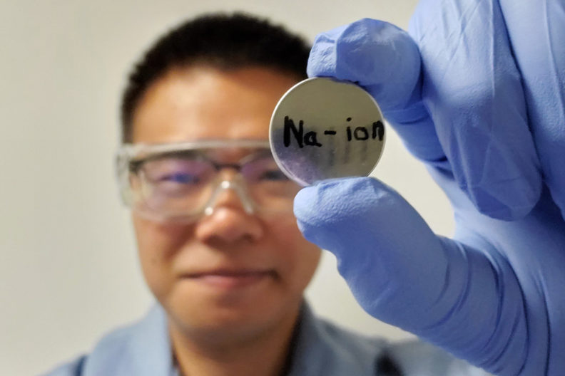 WSU PhD graduate Junhua Song hold a sodium-ion battery in two fingers.