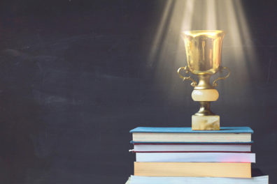 A shiny award resting on a stack of books.