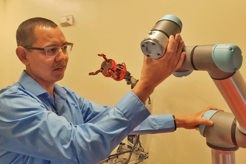 Man works with a mechanical arm in a laboratory.