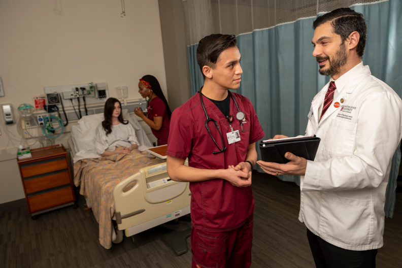 A doctor talks to a nurse in a room.