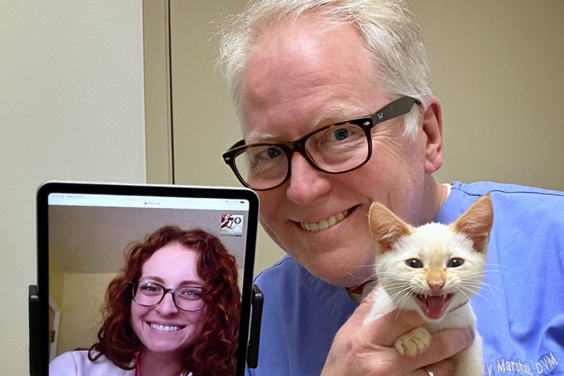 A student poses for a picture virtually with a veterinarian and a cat.