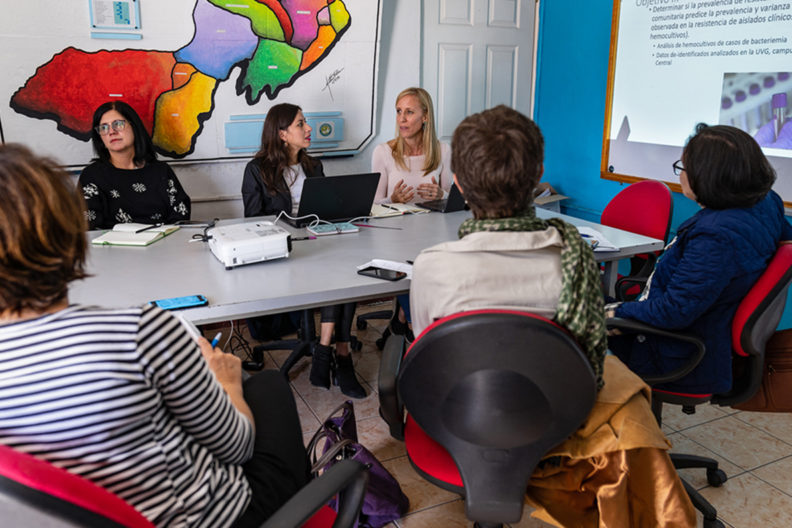 Women talking around a conference table.
