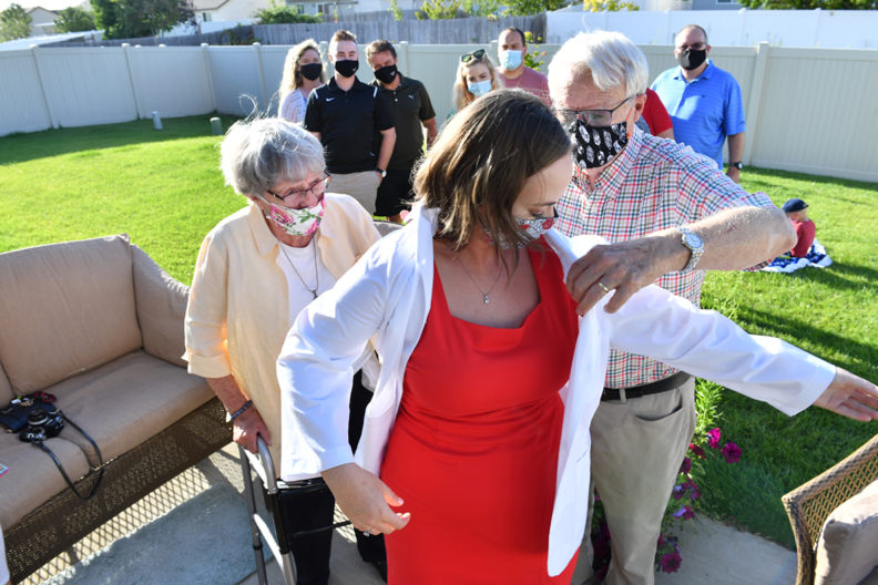 Dr. Robert West helps his granddaughter Martha Oberg don a white coat.