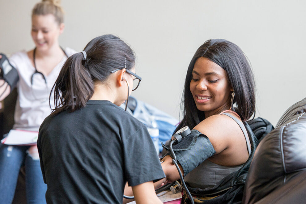 A nurse takes a woman's blood pressure.