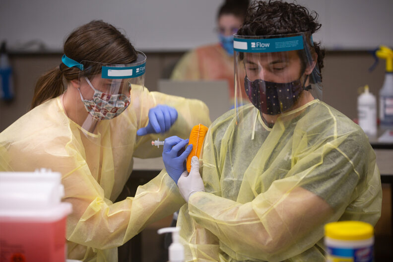 A pharmacy student practices giving a flu shot injection.