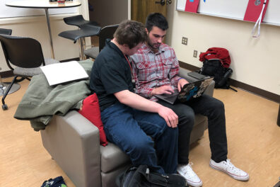 A WSU ROAR student looks at the screen as he and a practicum student work on a laptop.