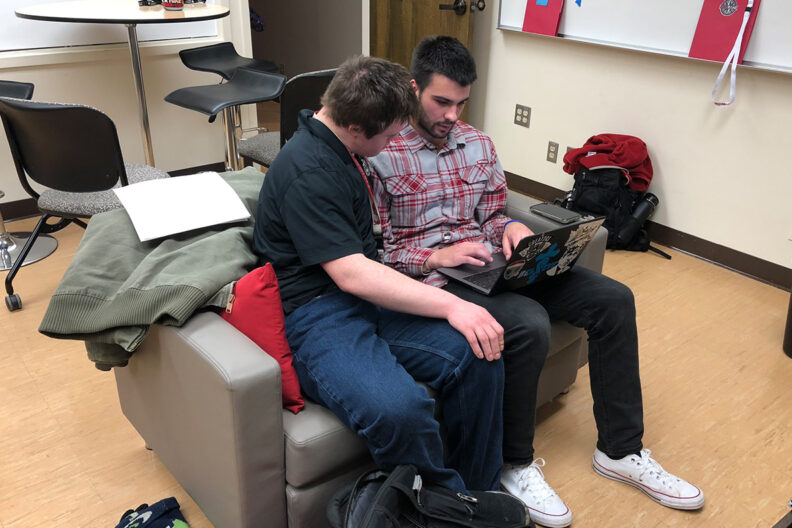 A WSU ROAR student looks at the screen as he and a practicum student work on a laptop.