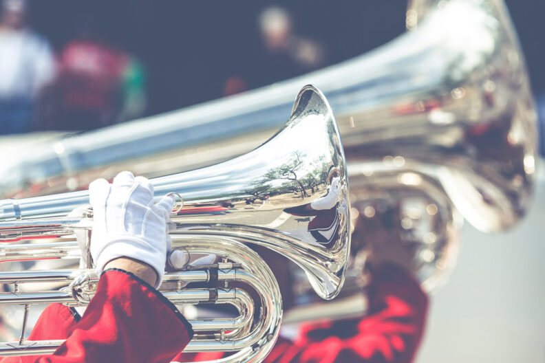 Two large brass horns being played by a military band