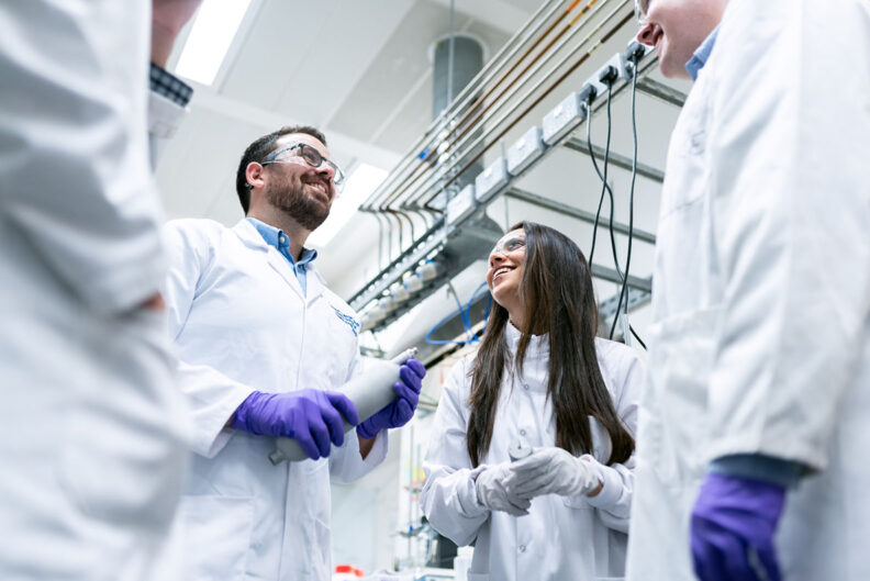 two students in lab coats smiling