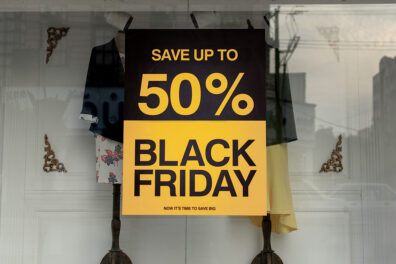 A retail clothing store window with a Black Friday 50% off sale sign