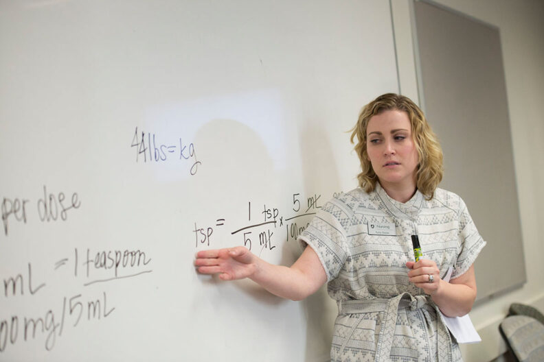 Professor gesturing to equations on a whitebord