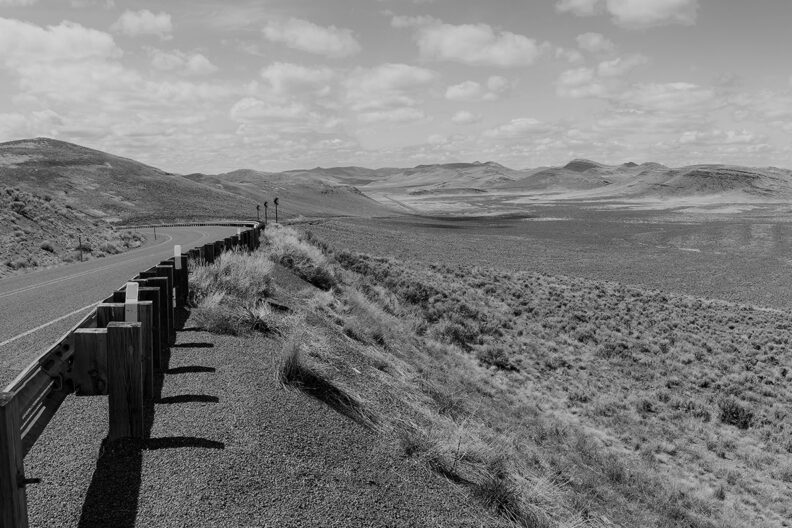 Black and white photo of roadside and rural landscape in Malheur County, Oregon.