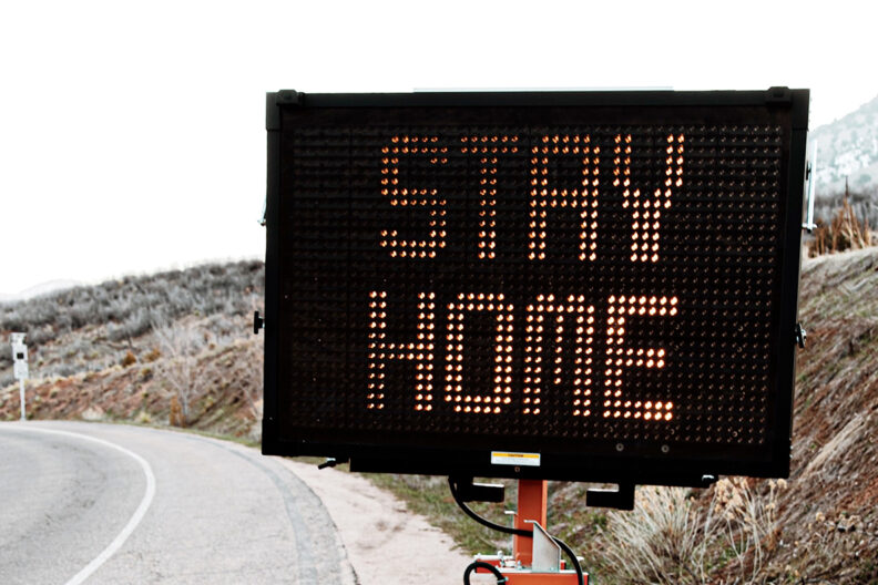 Traffic sign on roadside that reads 'Stay Home'.