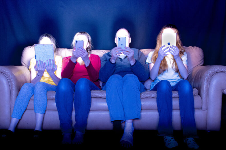 A family looks at mobile devices on a couch