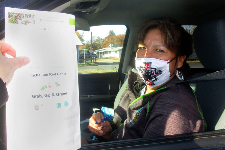 A woman receives Inchelium Red garlic at a drive-through event.