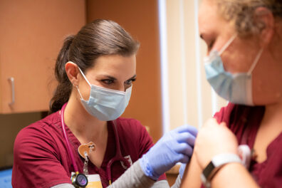 A nursing student gives a COVID-19 vaccine.