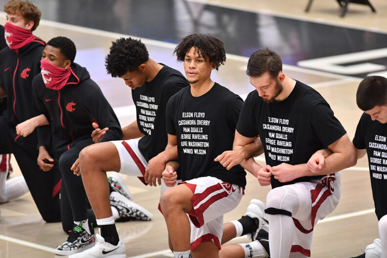 WSU men's basketball team kneeling on court with locked arms.