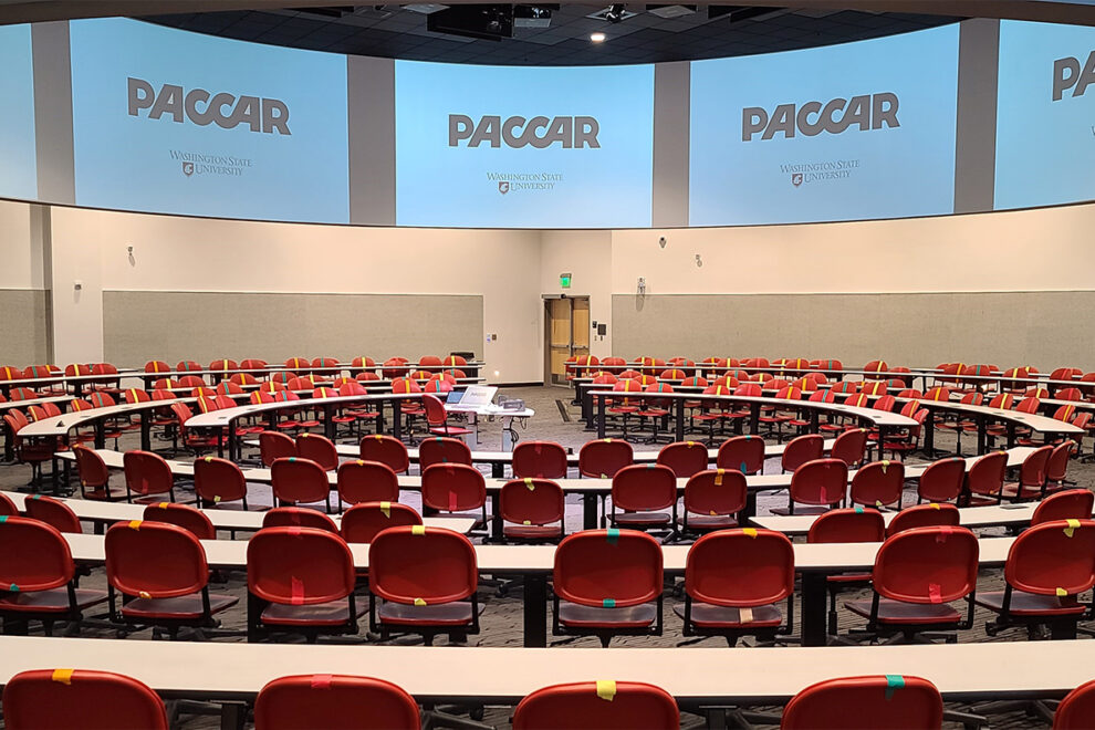 Rows of empty tables and chairs inside the PACCAR Lecture Hall.