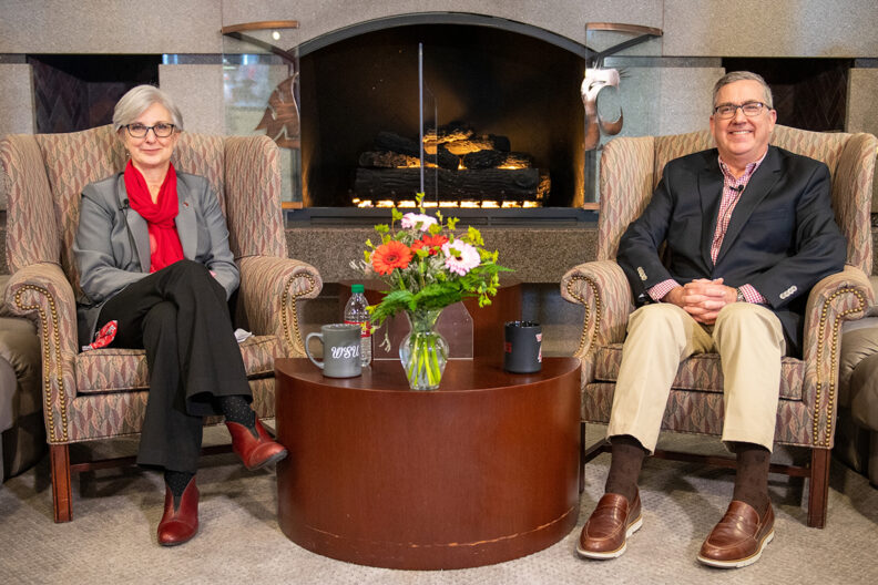 WSU President Kirk Schulz and WSU Provost Elizabeth Chilton sitting in chairs next to a fireplace.