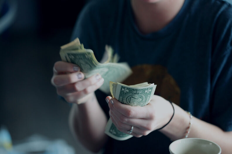 Closeup of a woman's hands while counting U.S. dollars.