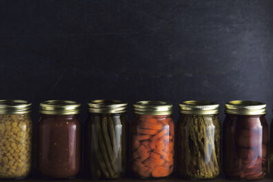 A row of various foods in canning jars.