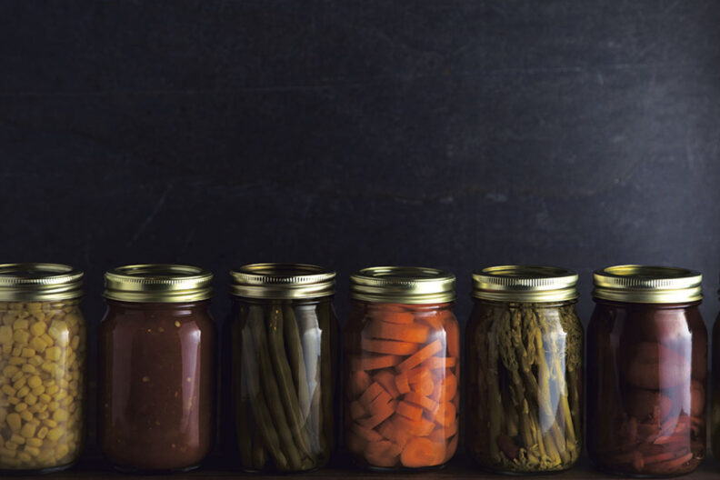 A row of various foods in canning jars.