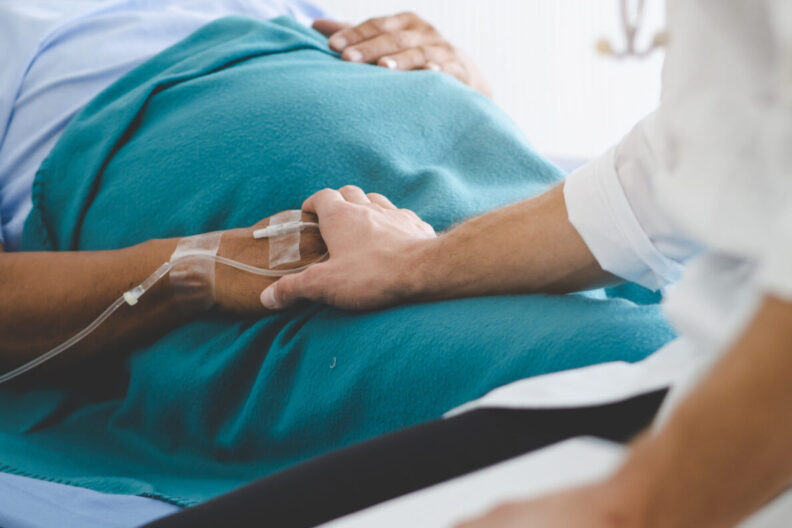 A healthcare worker holding the hand of a hospital patient.