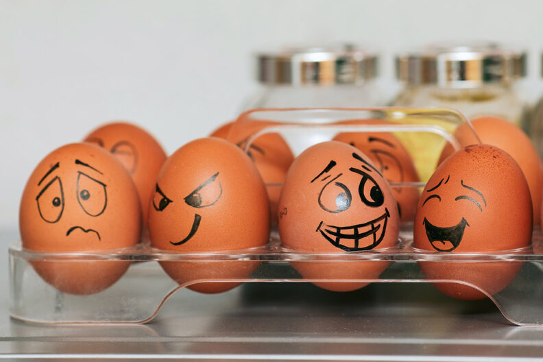 Brown eggs with different emotional facial expressions drawn on them.