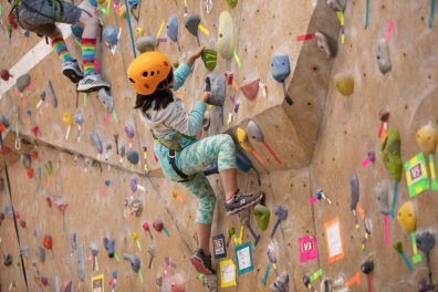 A kid makes her way up a climbing wall