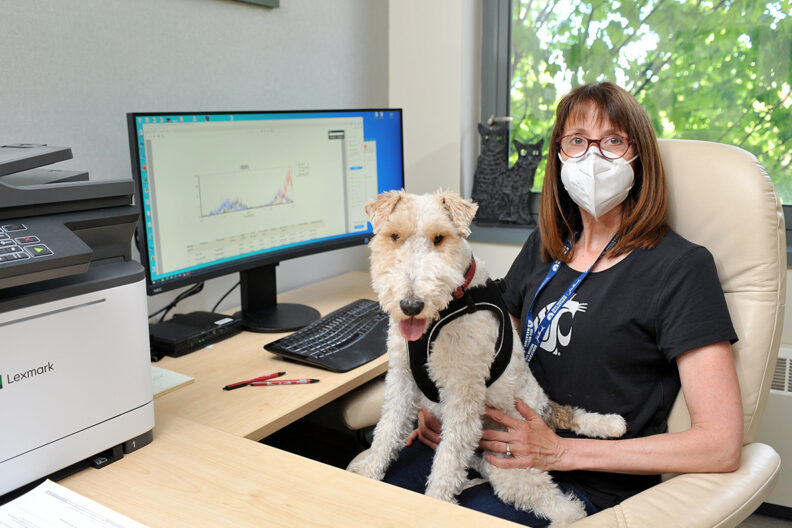 Dr. Katrina Mealey sitting at a desk with her dog, Borghi, on her lap.
