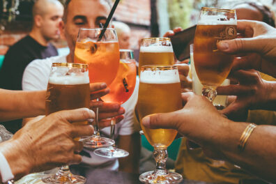Hands holding beers and cocktails raised in a toast