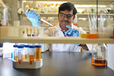 Kathir Selvam in a research lab holding a pipette.