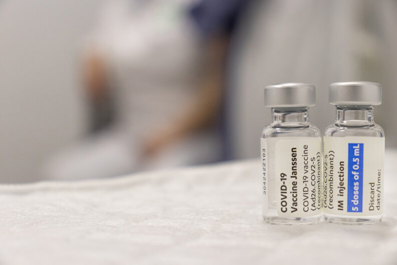 Two vials of COVID-19 vaccine on a white table.