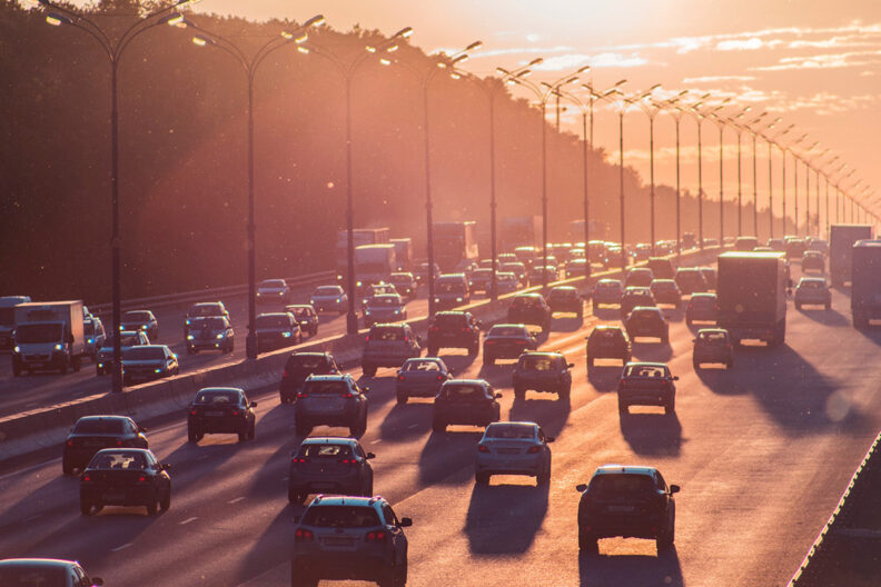 Several lanes of traffic on a major roadway filled with cars traveling in opposite directions.