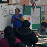 A photo of a parent talking at the front in a classroom of adults