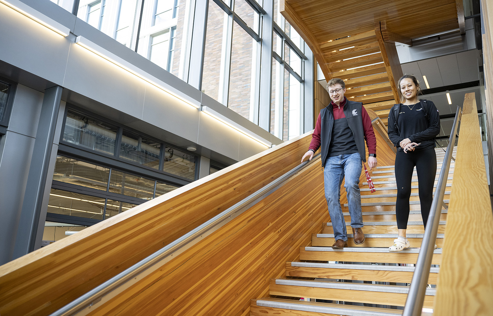 Dos personas bajan por una escalera en un edificio académico de WSU Everett.