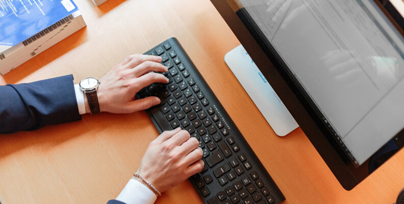 bird's eye view of person typing on keyboard in front of screen