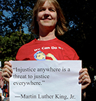 Sue Peabody holds sign with MLK quote "Injustice anywhere is a threat to justice everywhere."