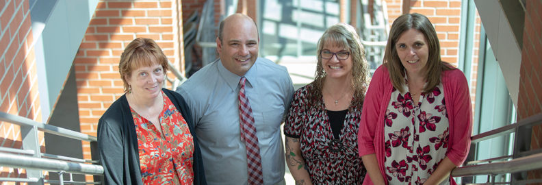All four of the Field Services team smiling on the Ed Ad stairs