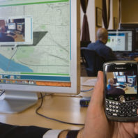 Orest Piskalns uses his BlackBerry to photograph co-worker Kevin Karpenske ’08 and show how MapWith.Us technology works. He uploads an image and then, using the phone’s Global Positioning System coordinates, pinpoints Karpenske’s location.