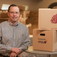 Dave Wilson '86 with WSU-themed boxes for graduates, produced by Spokane Packaging. Photo Robert Hubner
